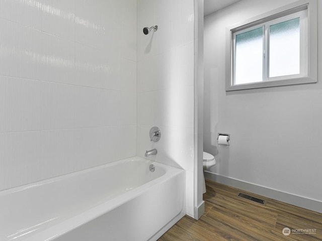 bathroom with tiled shower / bath, wood-type flooring, and toilet