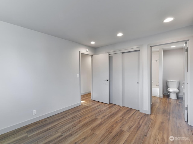 unfurnished bedroom featuring dark wood-type flooring, a closet, and ensuite bathroom