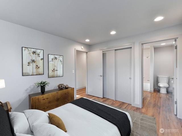 bedroom with hardwood / wood-style flooring, ensuite bathroom, and a closet