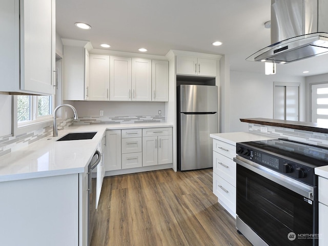 kitchen featuring electric stove, island range hood, stainless steel refrigerator, and white cabinets