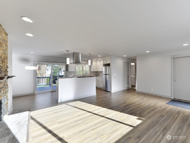 kitchen featuring white cabinetry, island range hood, stainless steel fridge, and pendant lighting