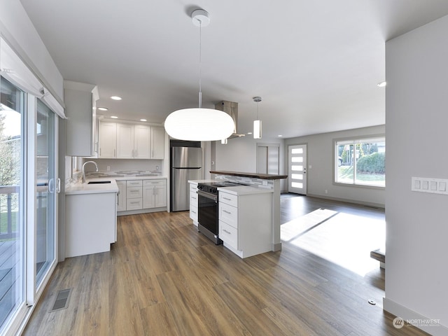 kitchen featuring sink, hanging light fixtures, appliances with stainless steel finishes, dark hardwood / wood-style flooring, and white cabinets