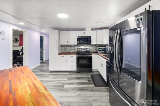 kitchen with wooden counters, tasteful backsplash, white cabinetry, and black appliances