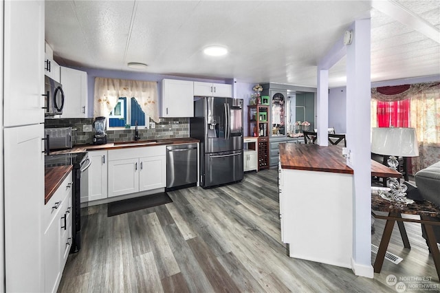 kitchen featuring white cabinetry, sink, wooden counters, backsplash, and black appliances