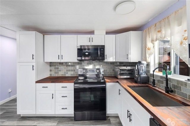 kitchen featuring stainless steel appliances, white cabinetry, sink, and wooden counters