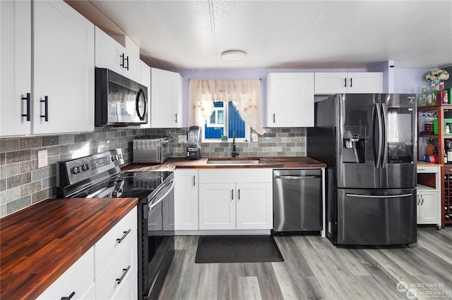 kitchen featuring white cabinets, sink, butcher block counters, and stainless steel appliances