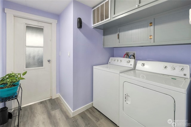 washroom featuring washer and clothes dryer, light hardwood / wood-style floors, and cabinets