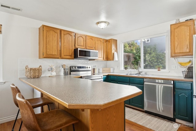 kitchen featuring tasteful backsplash, appliances with stainless steel finishes, kitchen peninsula, and a breakfast bar area