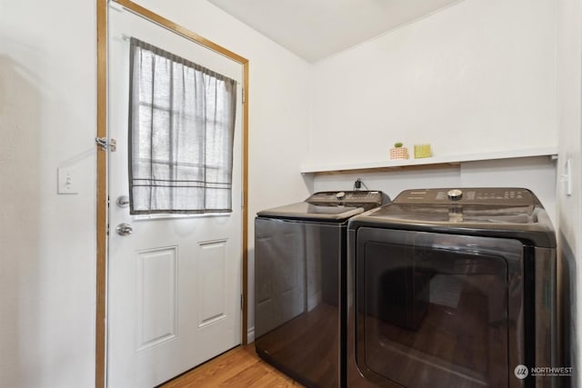 laundry area featuring washing machine and clothes dryer and light wood-type flooring