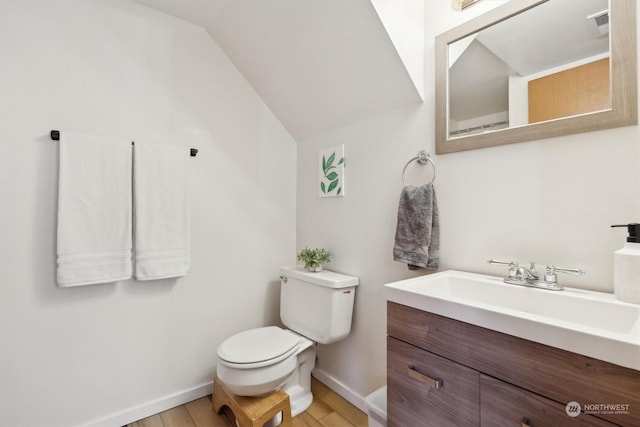 bathroom with hardwood / wood-style flooring, lofted ceiling, toilet, and vanity