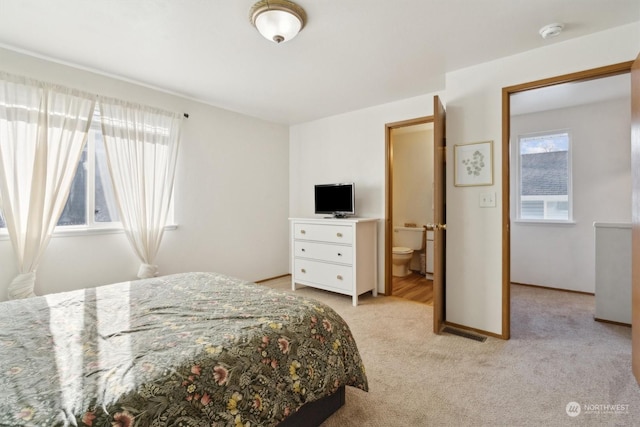 bedroom with ensuite bath, light carpet, and multiple windows