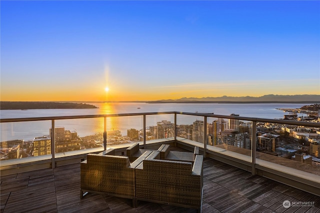 balcony at dusk featuring a water view