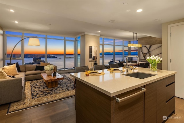 kitchen with sink, a center island with sink, dishwasher, and a water view