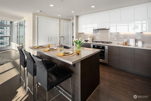 kitchen featuring white cabinetry, sink, a kitchen bar, stainless steel oven, and gas cooktop