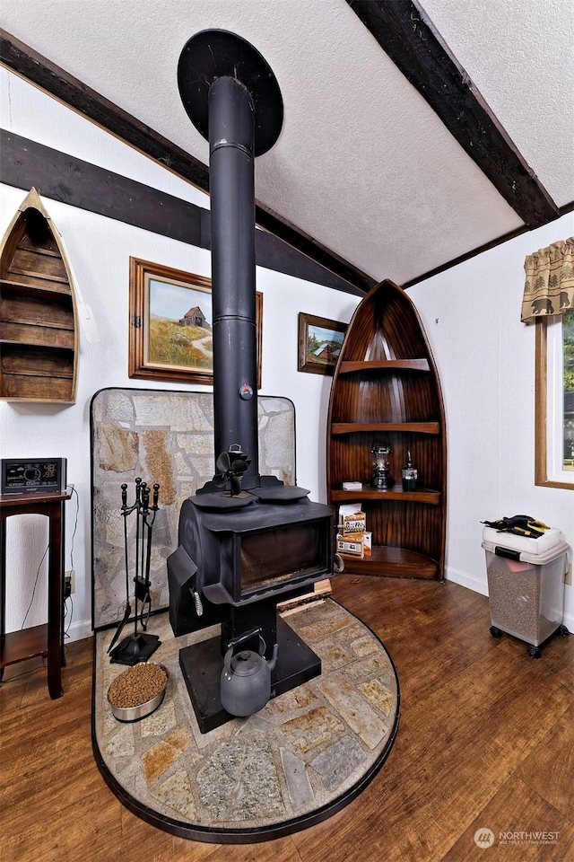 interior details with beam ceiling, wood-type flooring, a textured ceiling, and a wood stove