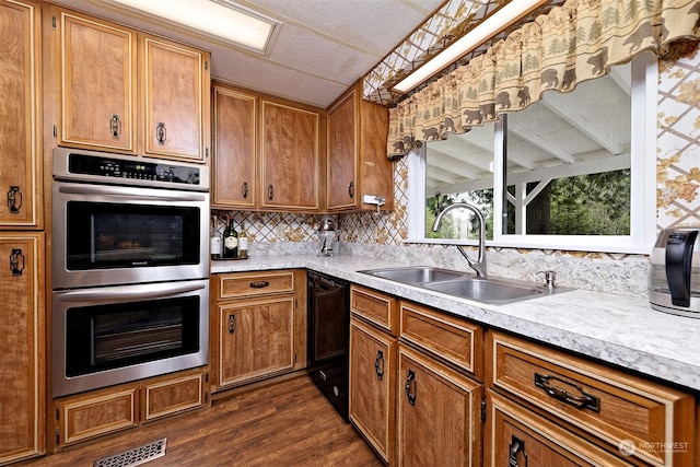 kitchen with dark hardwood / wood-style floors, double oven, black dishwasher, sink, and a textured ceiling