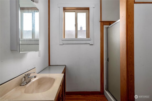 bathroom with a wealth of natural light, a shower with door, hardwood / wood-style flooring, and vanity