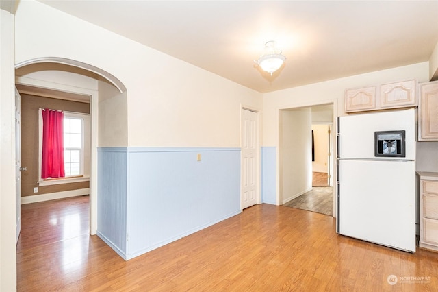 kitchen featuring light wood-type flooring, white refrigerator with ice dispenser, and light brown cabinetry