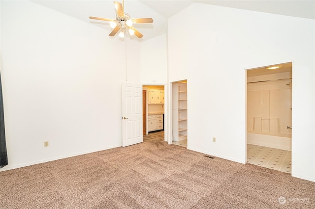 carpeted empty room featuring ceiling fan and high vaulted ceiling