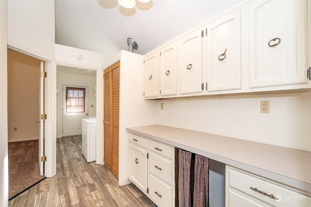 kitchen featuring washer / dryer, white cabinetry, and hardwood / wood-style flooring