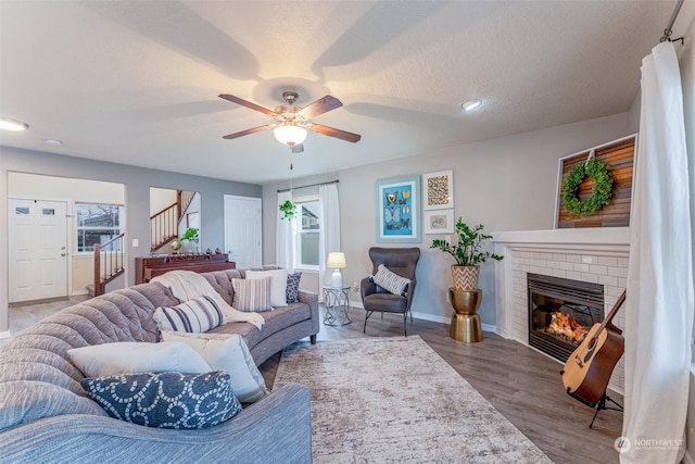 living room with a brick fireplace, ceiling fan, a healthy amount of sunlight, and hardwood / wood-style flooring