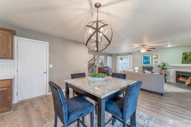 dining space with a textured ceiling, light hardwood / wood-style flooring, and ceiling fan with notable chandelier