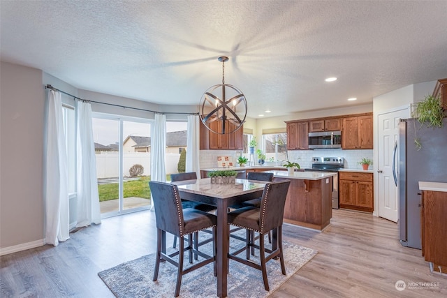 dining space featuring light wood-type flooring, a textured ceiling, and a notable chandelier