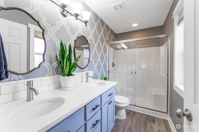 bathroom with hardwood / wood-style flooring, vanity, toilet, and a shower with door