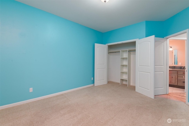 unfurnished bedroom with ensuite bath, light colored carpet, and a closet