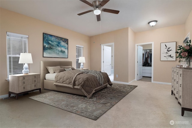 bedroom with a walk in closet, light carpet, a closet, ceiling fan, and ensuite bathroom