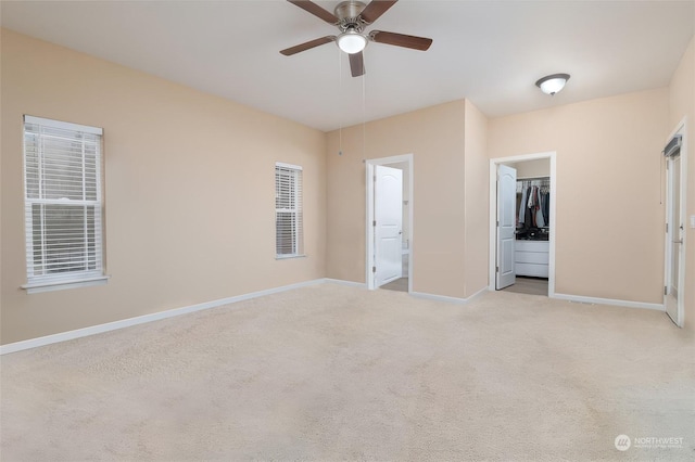 unfurnished bedroom with a spacious closet, ceiling fan, light carpet, and connected bathroom