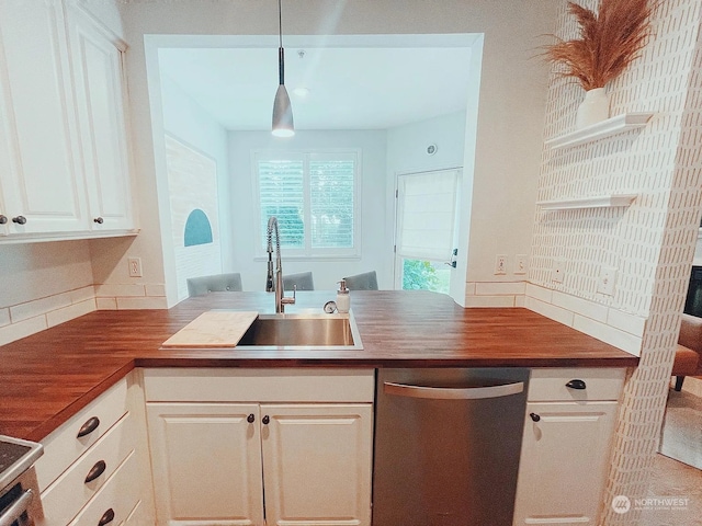 kitchen featuring pendant lighting, sink, wooden counters, white cabinets, and stainless steel dishwasher