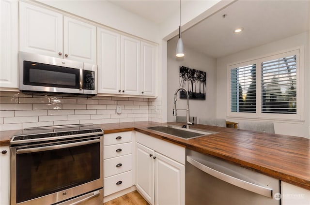 kitchen with white cabinetry, appliances with stainless steel finishes, sink, and butcher block countertops