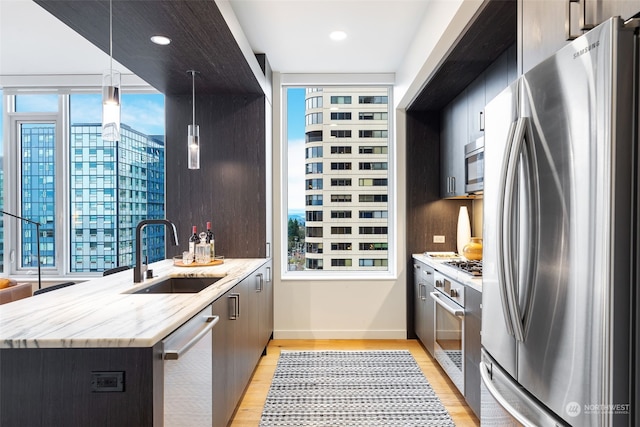 kitchen featuring sink, stainless steel appliances, decorative light fixtures, and a wealth of natural light