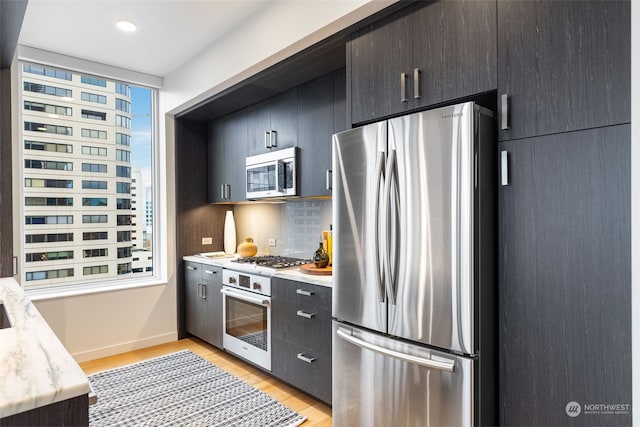 kitchen with light wood-type flooring, appliances with stainless steel finishes, and tasteful backsplash