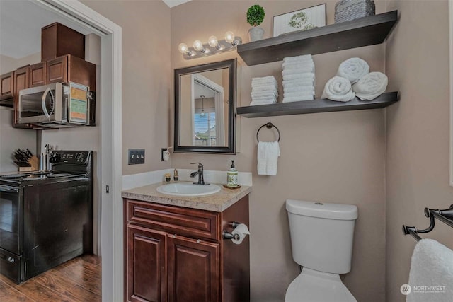 bathroom featuring toilet, vanity, and hardwood / wood-style floors