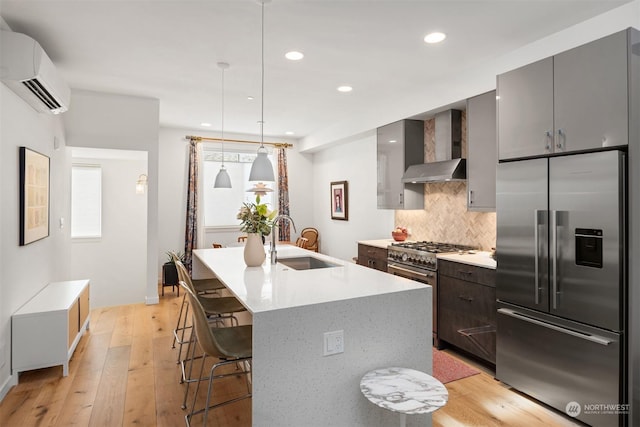 kitchen with decorative light fixtures, tasteful backsplash, wall chimney range hood, premium appliances, and a wall mounted air conditioner