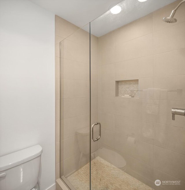 bathroom featuring toilet and an enclosed shower