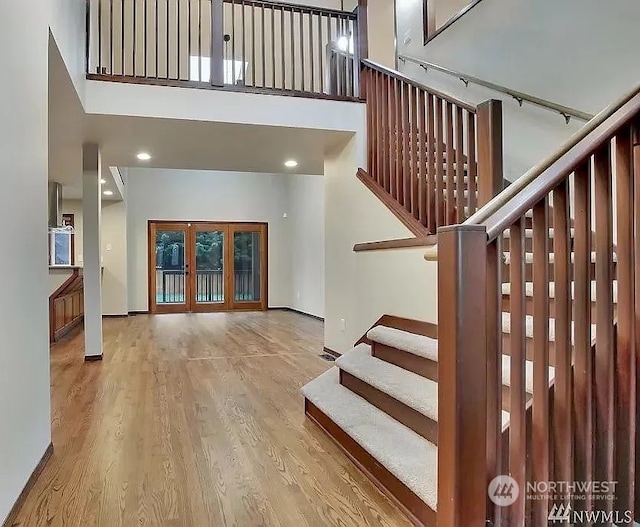 staircase with french doors, a high ceiling, and hardwood / wood-style flooring