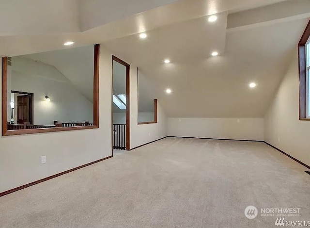 additional living space featuring light carpet and vaulted ceiling