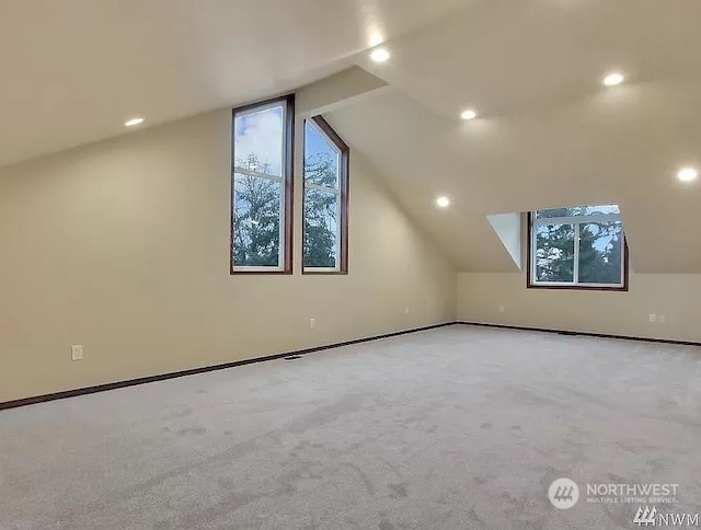 additional living space with light colored carpet and vaulted ceiling