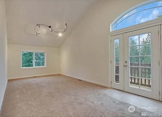 interior space featuring light colored carpet, rail lighting, and vaulted ceiling