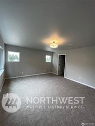 unfurnished bedroom featuring multiple windows and dark carpet