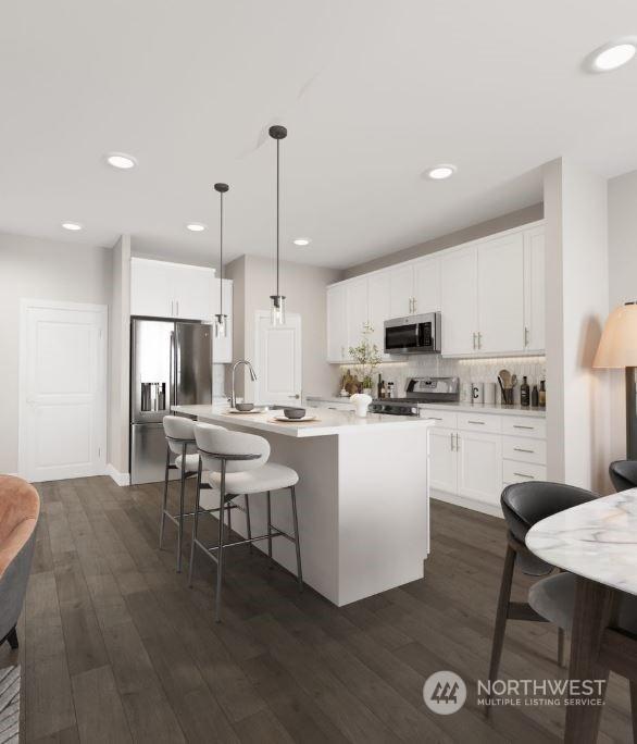 kitchen featuring decorative light fixtures, white cabinets, dark hardwood / wood-style flooring, and stainless steel appliances