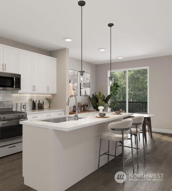 kitchen featuring hanging light fixtures, sink, white cabinets, a kitchen island with sink, and stainless steel appliances