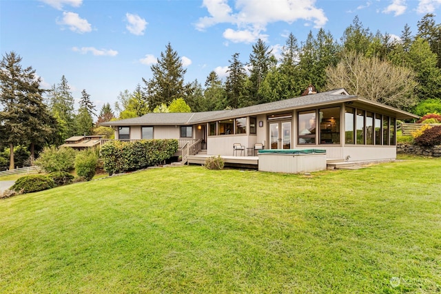 rear view of property with a wooden deck, a sunroom, and a yard