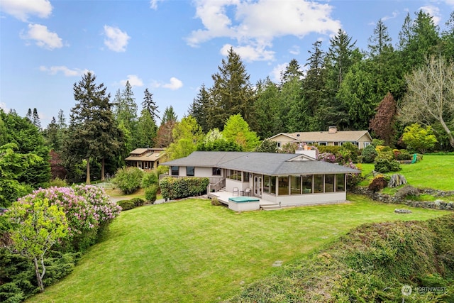 rear view of property with a sunroom and a lawn