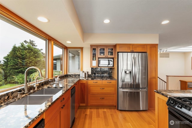 kitchen with stone counters, sink, appliances with stainless steel finishes, and light hardwood / wood-style flooring