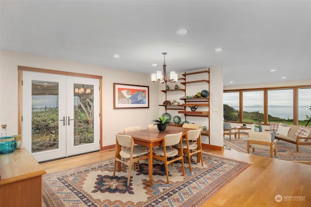 dining space with a notable chandelier, light wood-type flooring, and french doors