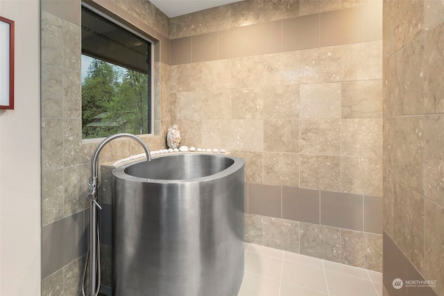 bathroom featuring tile patterned flooring, a bathtub, and tile walls